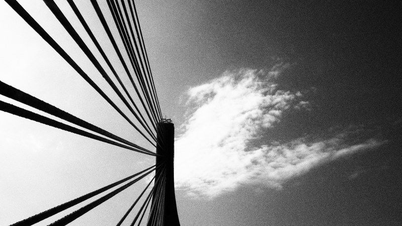 black and white shot of steel bridge architecture from below with cloudy sky from below, metal bridge and sky 4k