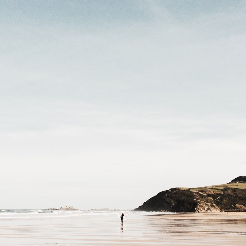 a distant person in the sea in front of a coastal rock at zarautz pas vasco espana, enjoying the sea 4k