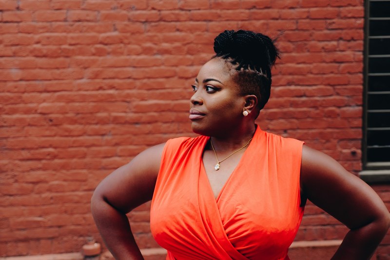 a woman in a bun places her hands on her hips before a red brick wall, woman with hands on her hips 4k
