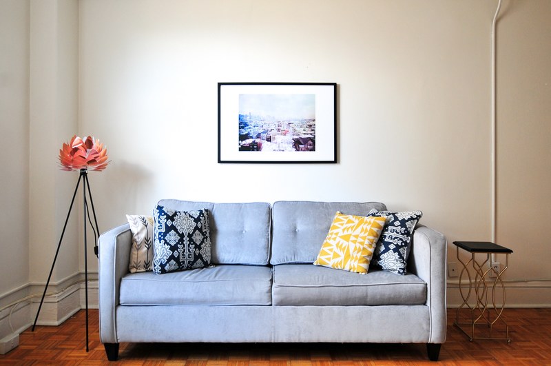 gray couch with decorative pillows and unique art in a cozy apartment living room, at home 4k