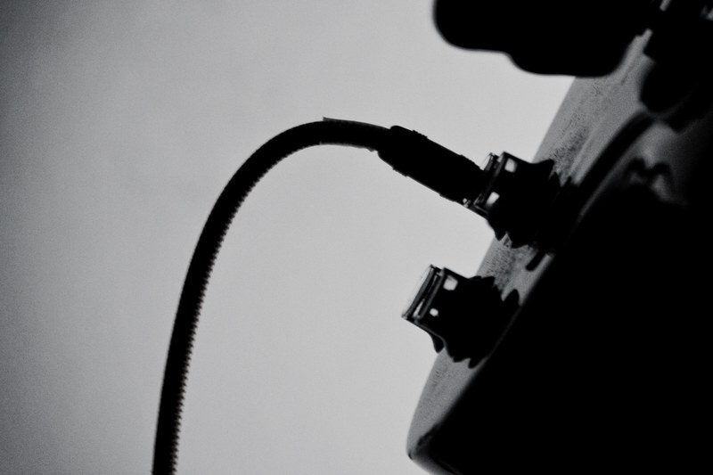 a black and white shot of a wire plugged in into a guitar, guitar wire in black and white 4k