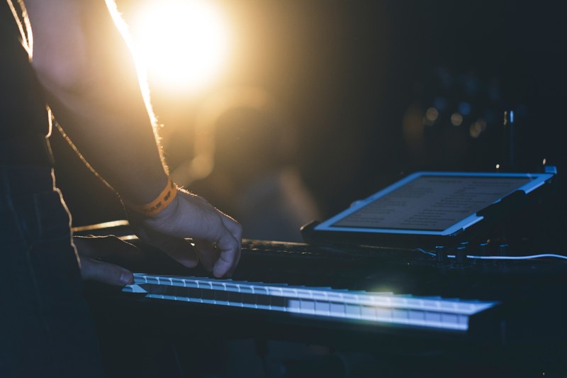 a close up of a man playing the keyboard with a tablet in front of him, keyboard player with a tablet 4k