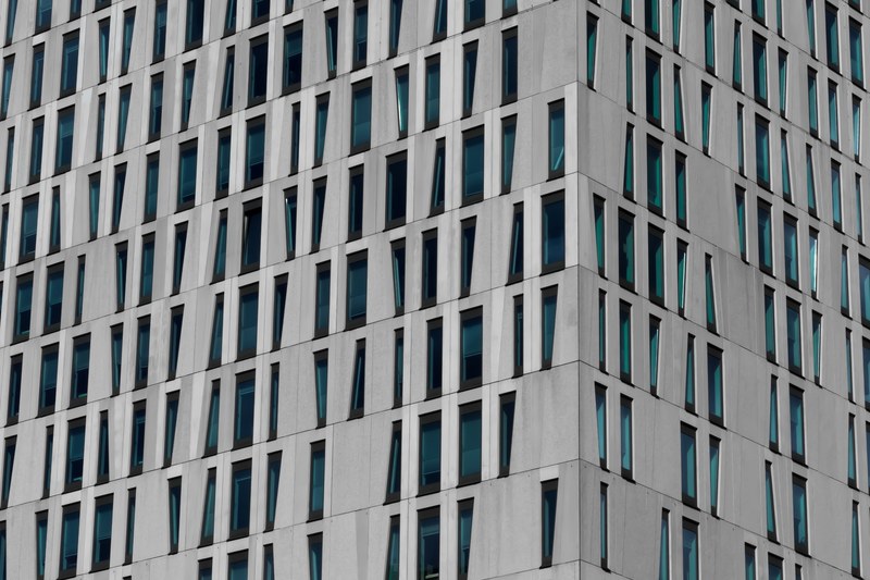 a gray building facade with windows in various shapes in rotterdam, gray office building facade 4k