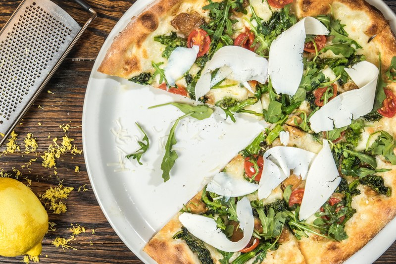 a slice taken from a pizza with cherry tomatoes leaves mozzarella cheese and grated lemon, pizza for high end italian restaurant 4k