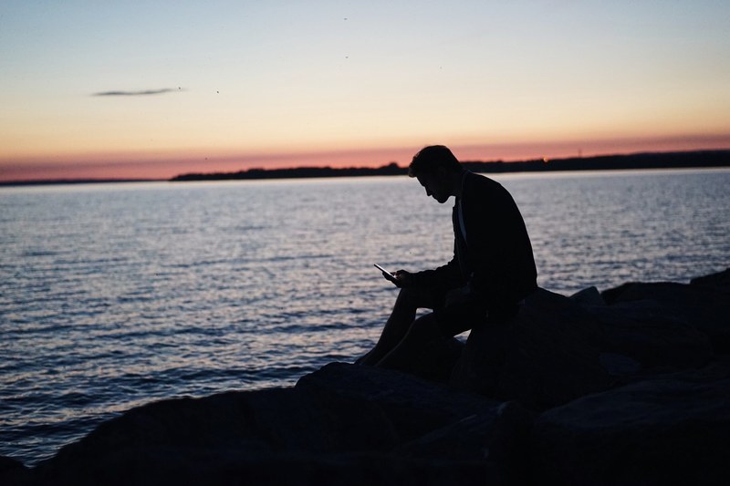 man silhouette using smartphone on the rock by the ocean after the sunset at britannia beach, silhouette using smartphone 4k