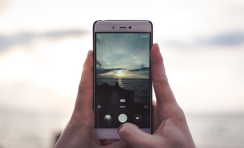 a person taking a picture of the ocean under clouds, _taking picture ocean 4k