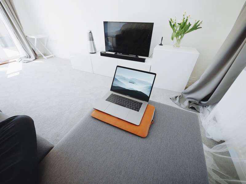 a macbook on a gray sofa in a living room, laptop in the living room 4k