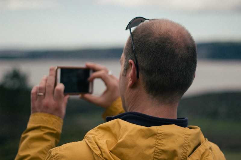man taking a picture of the landscape on is iphone, taking an iphone picture 4k