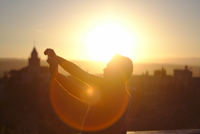 man shooting backlit selfie near alhambra during sunset, man taking backlit selfie 4k