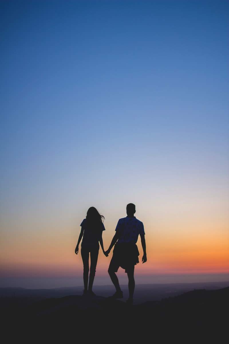 a couple in silhouette walks on a beach during a brilliant sunset, sunset beach couple 4k