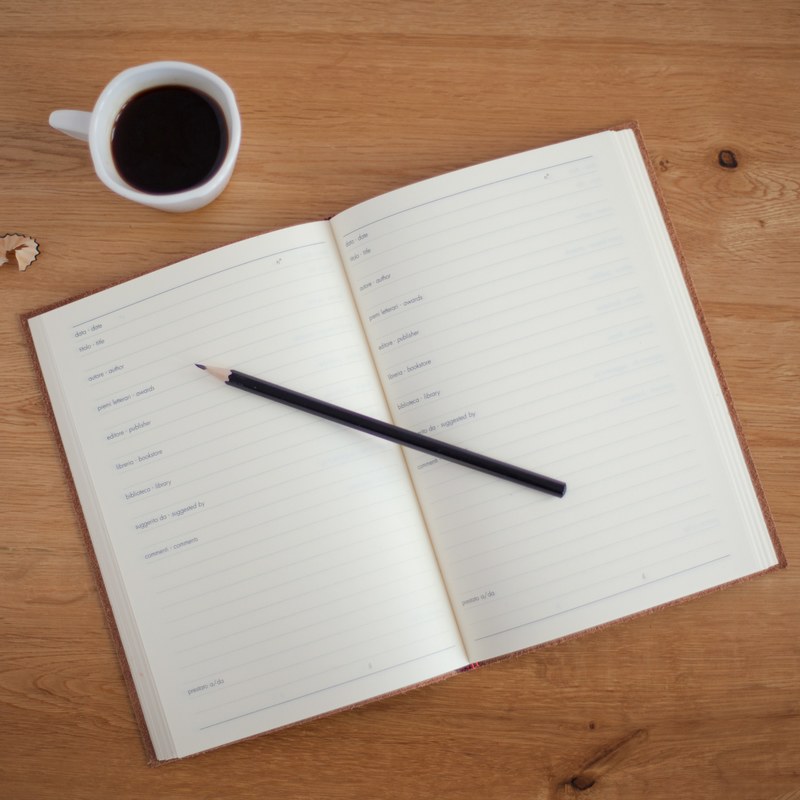 an overhead shot of a pencil on an open planner next to a cup of coffee, planning over coffee 4k