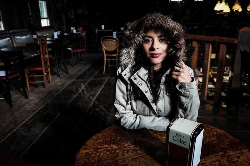 a woman in a fur lined coat sits in a table at a dark and empty restaurant, woman in empty restaurant 4k