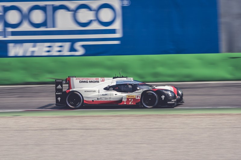 white and red racecar with logos speeds on a race track with a blurry background, racecar on track 4k