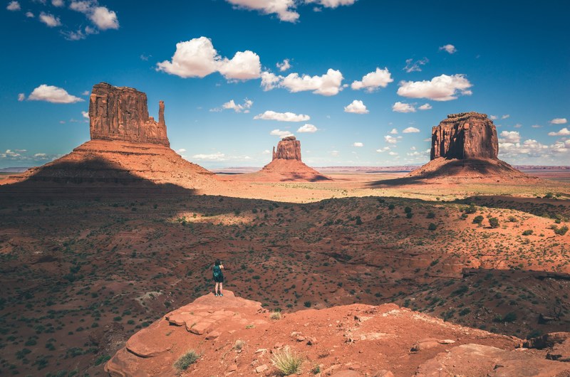 hiker stands atop a peak of a rock formation in the desert of oljato monument valley, seeking adventure 4k