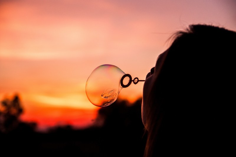 a woman blowing soap bubbles during sunset, blowing bubbles in the sunset 4k