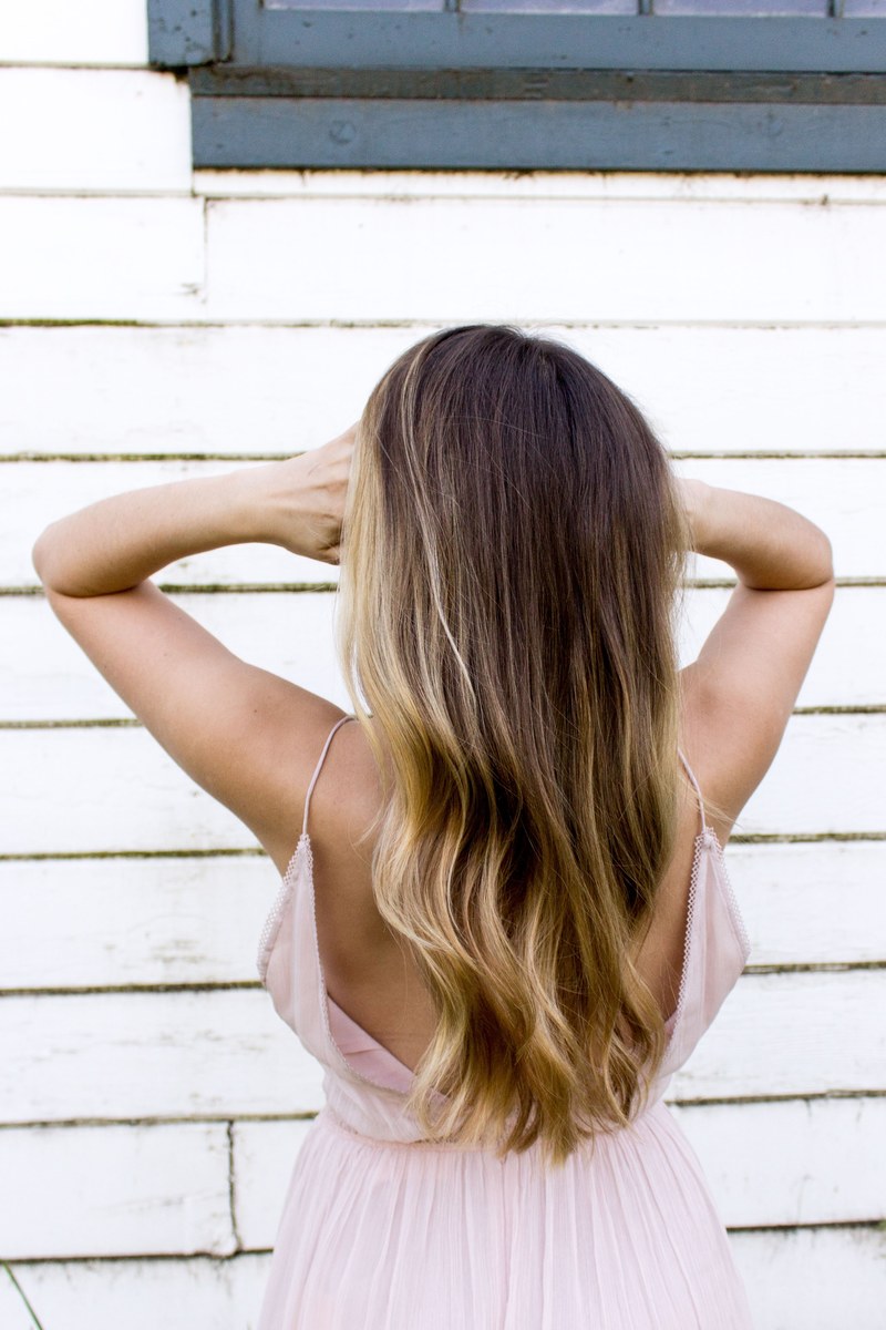 woman faced away shaking out her hair near a wall, looking away 4k