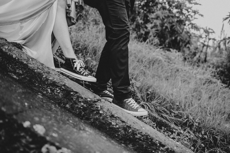 black and white shot of bride and groom wearing converse shoes walking down stairs near grass, wedding couple walking in converse 4k