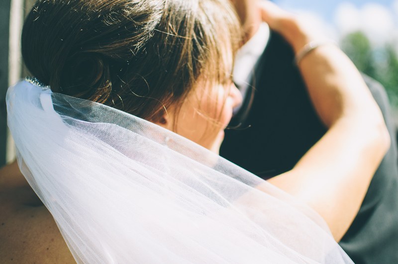 close up of a smiling bride in a veil facing away from the camera embracing the groom, close up bride in a veil 4k