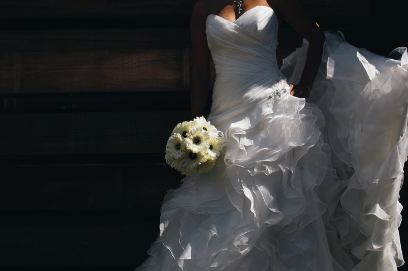 a bride holding her bouquet of daisies wearing a ruffled wedding dress, bride stands with daisies 4k