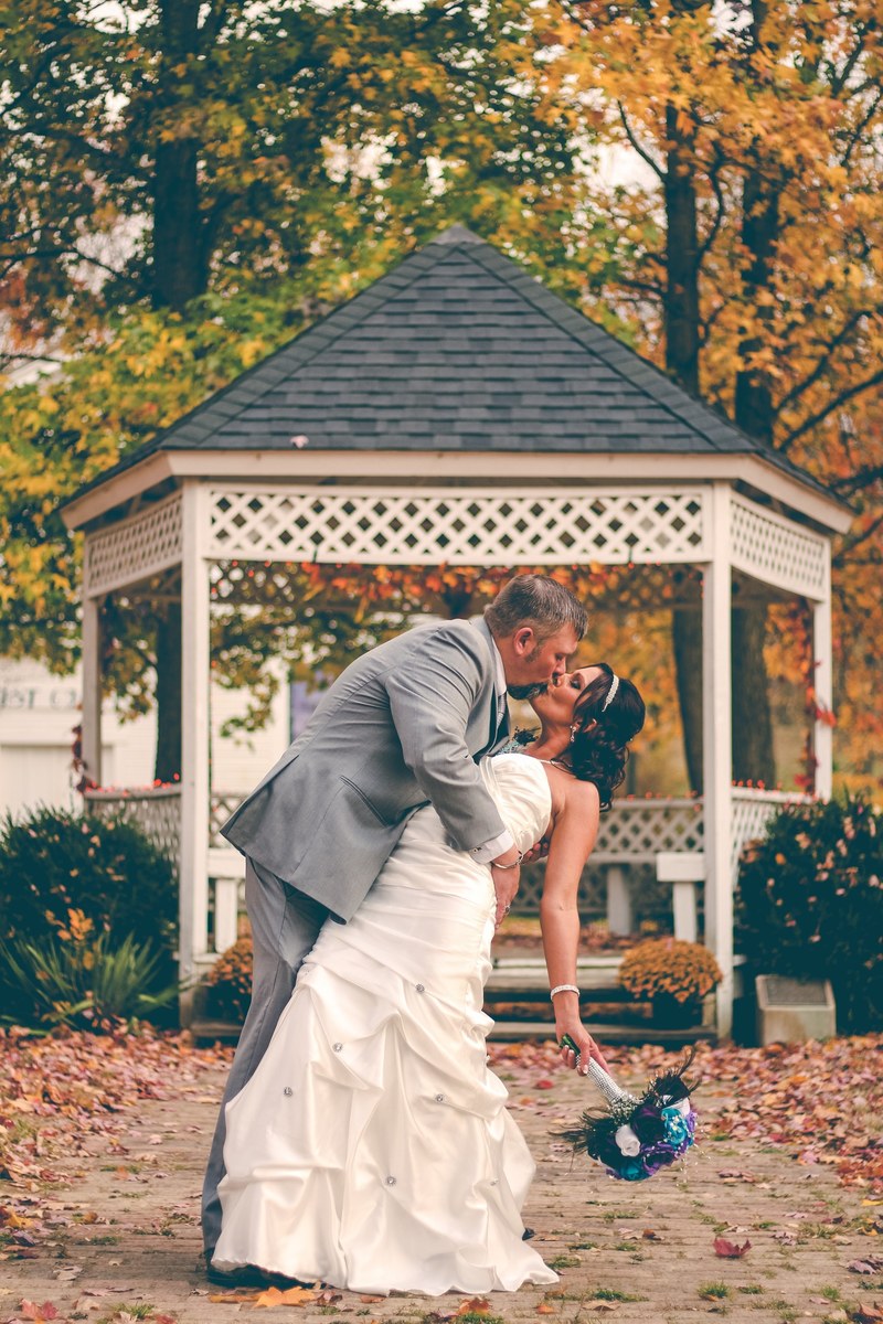 groom dips bride as they kiss in front of a gazebo, groom dips bride during kiss 4k