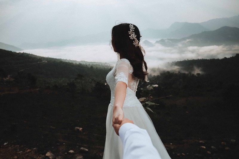 groom reaches his arm out to beautiful bride on vietnam mountain, love 4k