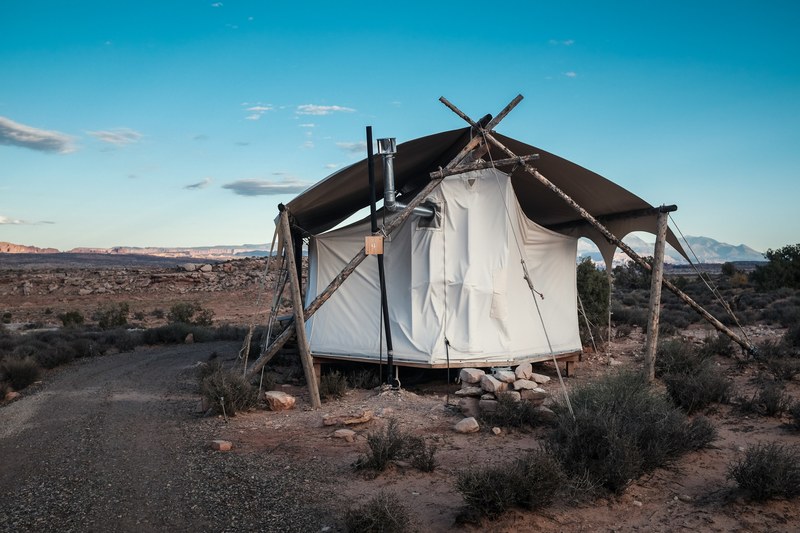 makeshift tent pitched in the desert along a dirt road with the clear blue sky in the background, all in a days work 4k