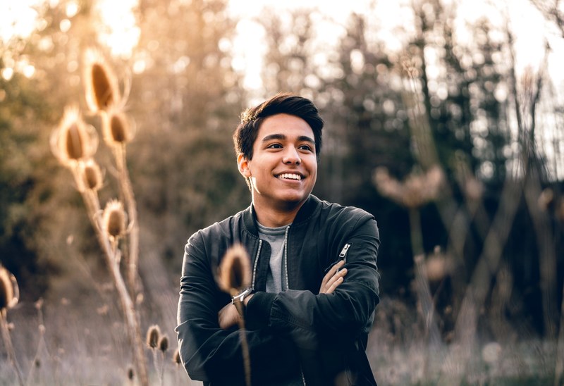a portrait of a smiling man with crossed arms in a grassy sunlit field, man with crossed arms 4k