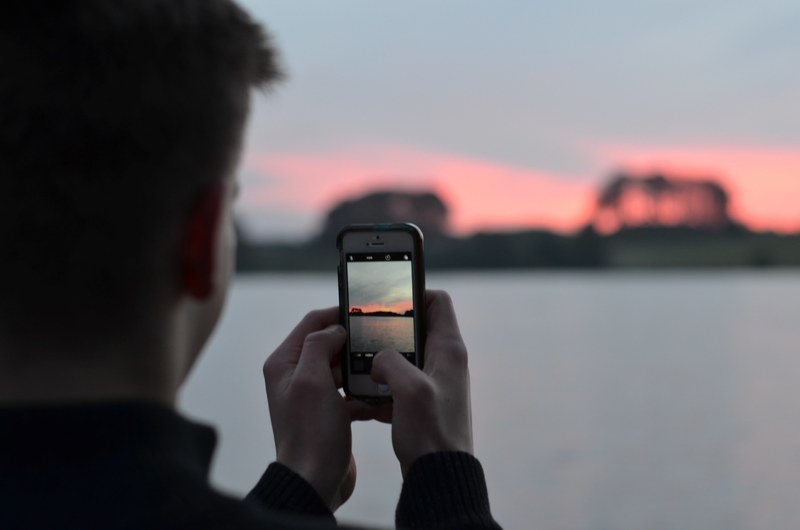 man shooting a photo with his iphone of a sunset in talkin tarn, shooting talkin tarn sunset 4k