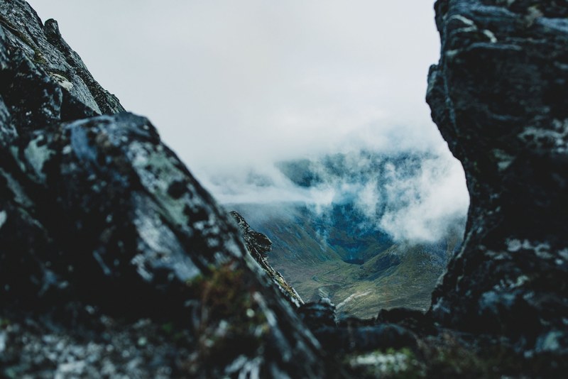peeking through mountains at a misty valley below, mountain valley seen through a rock gap 4k