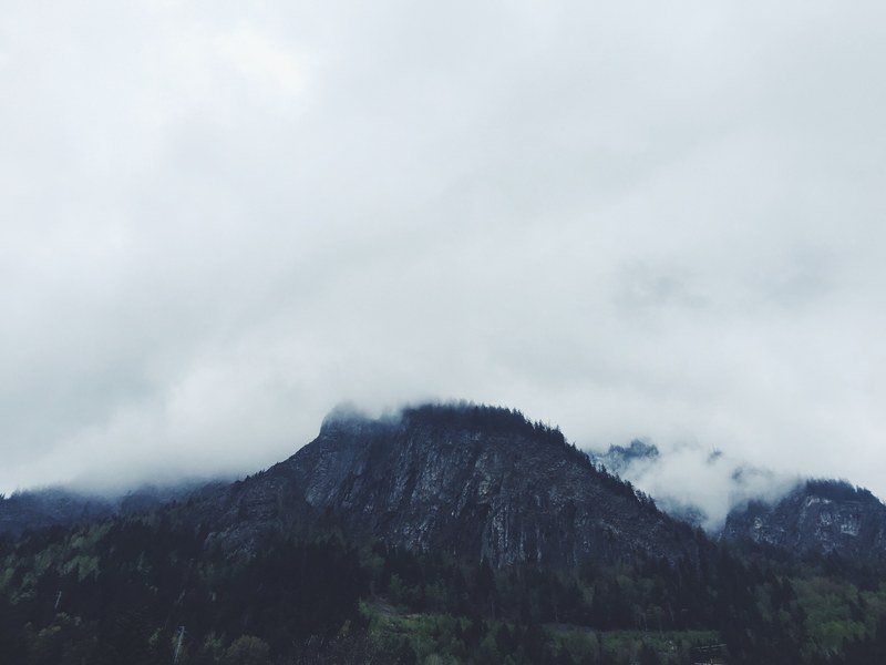 a jagged mountain shrouded in fog on a cloudy day, misty mountain 4k