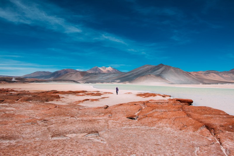 person walks toward mountains on the horizon of the atacama desert, walking through the desert 4k