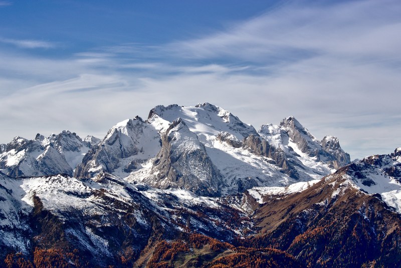 a jagged mountaintop covered in snow under a blue sky with wispy clouds, rocky snowy mountains 4k