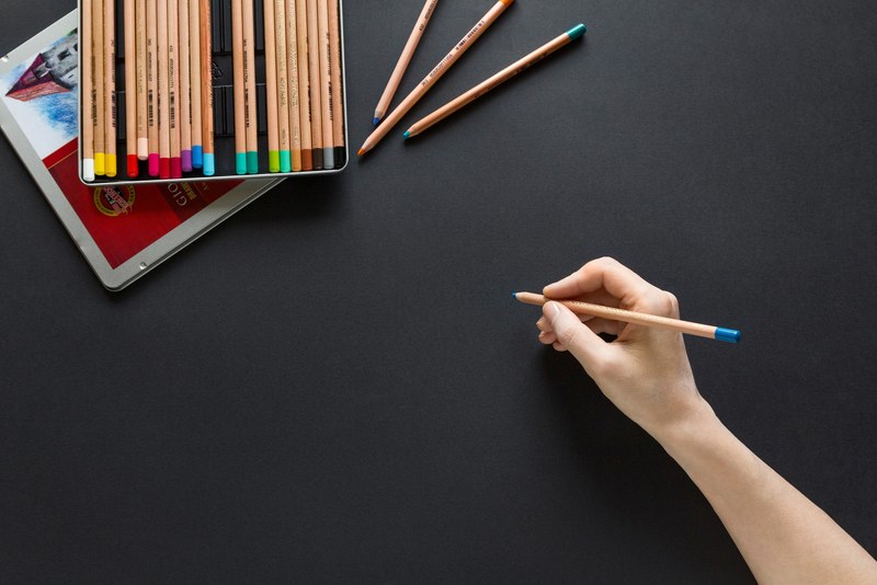 person holds blue pencil against black surface next to pencil set, blue pencil against black paper 4k