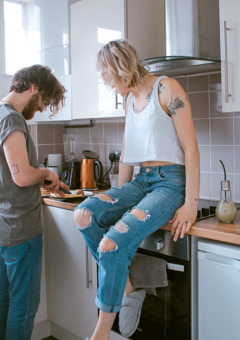 a woman sitting on the kitchen counter while watching a man prepare food, _cooking together 4k