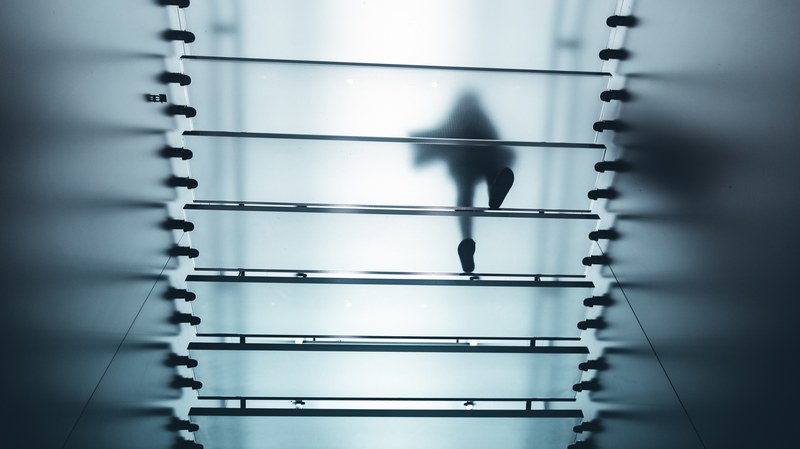a silhouette of a person walking on translucent glass steps seen from below, the cloud 4k