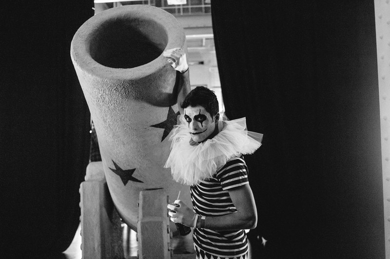 a clown in costume touching a cannon in a carnival in black and white in london, a clown with a cannon 4k