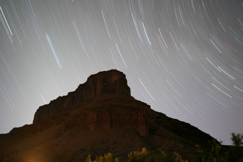 a long exposure shot of stars swirling around a rocky mountain in moab, moab mountain under a starry sky 4k