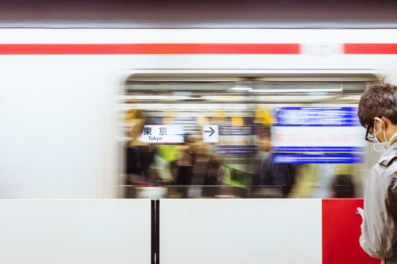 a blurry shot of a moving train in front of a man at the tokyo station, _man waits at tokyo station 4k