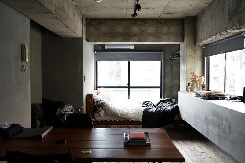 a small bedroom with a bed table chair phone and windows in shibuya, one bedroom apartment 4k