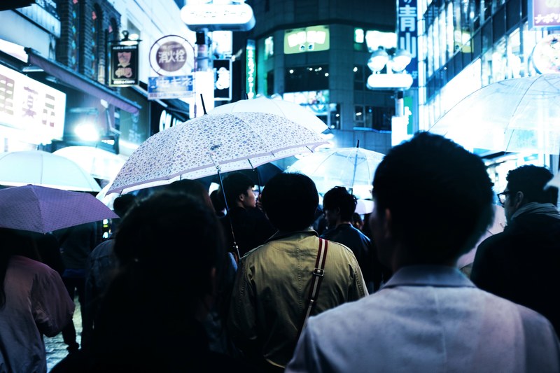 pedestrians with umbrellas in a well lit street in tokyos shibuya district, crowd holding umbrellas 4k