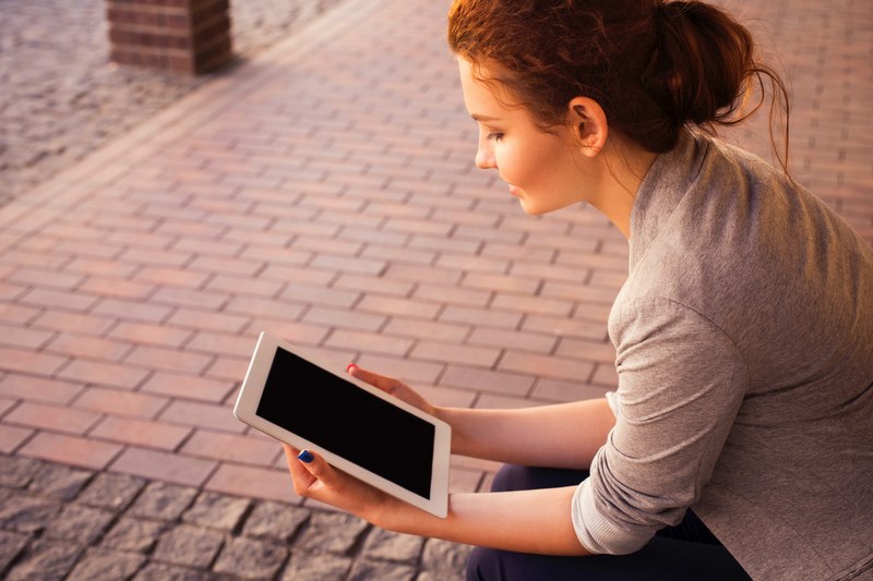 a woman with a blue painted nails holding and reading on an ipad tablet beside a walkway, woman with blue nails reading ipad 4k