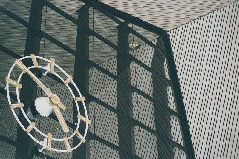 a big clock on a glass panel joining the ceiling and wall of diagonal tiles pattern, _time 4k