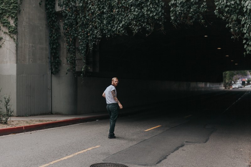 man with beard and tattoos standing in front of a tunnel road in los angeles, man walking into a tunnel 4k