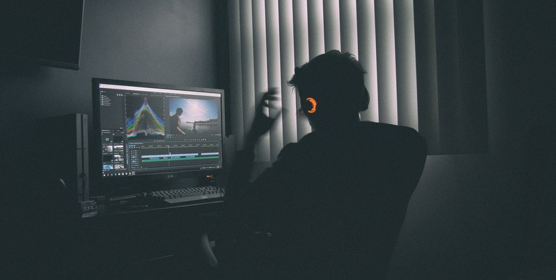 a man working on a computer while wearing red laser colored headphones, man working on computer 4k