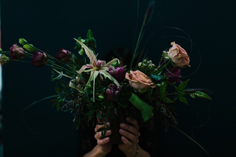 a person holding a large bouquet with pink roses and other flowers and leaves in front of their head, fall bouquet 4k