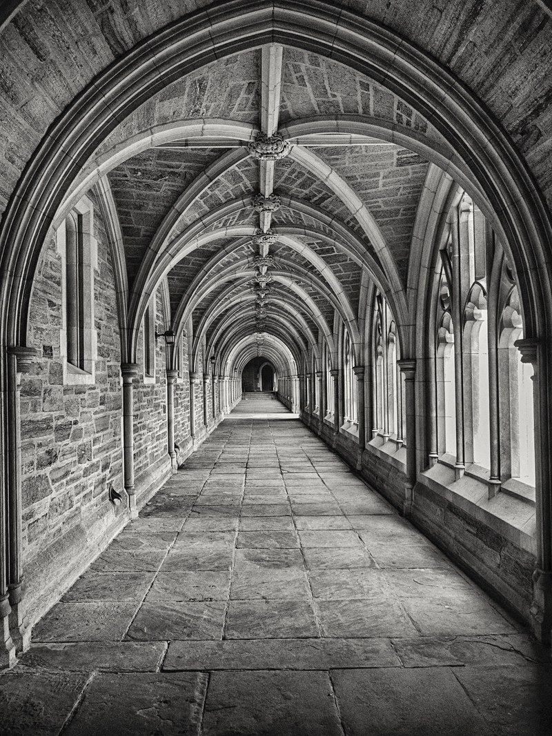 black and white shot of classic stone corridor architecture with archway, classic stone arched hallway 4k