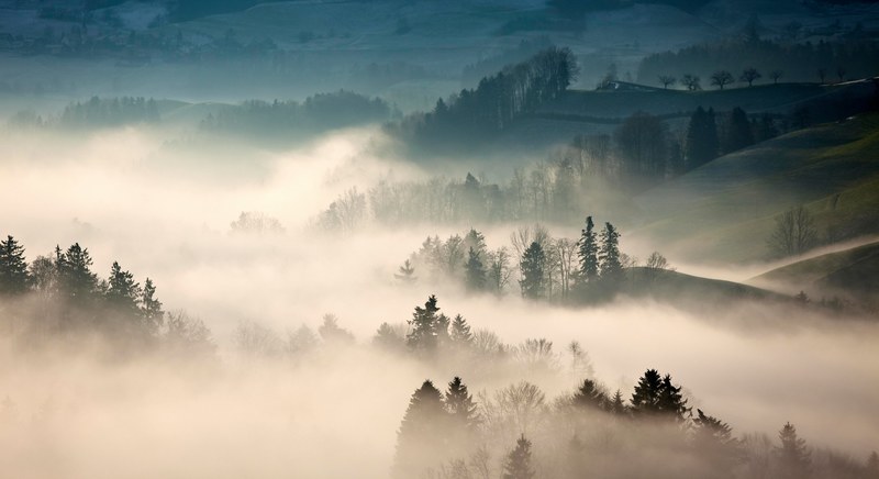 a hilly rural landscape wreathed in a dense fog, fog over the countryside 4k