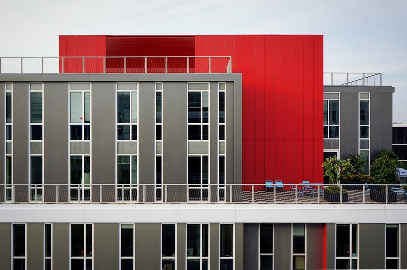 the exterior of a modern red and gray building with many windows and a checkered balcony, grey and red modern building 4k