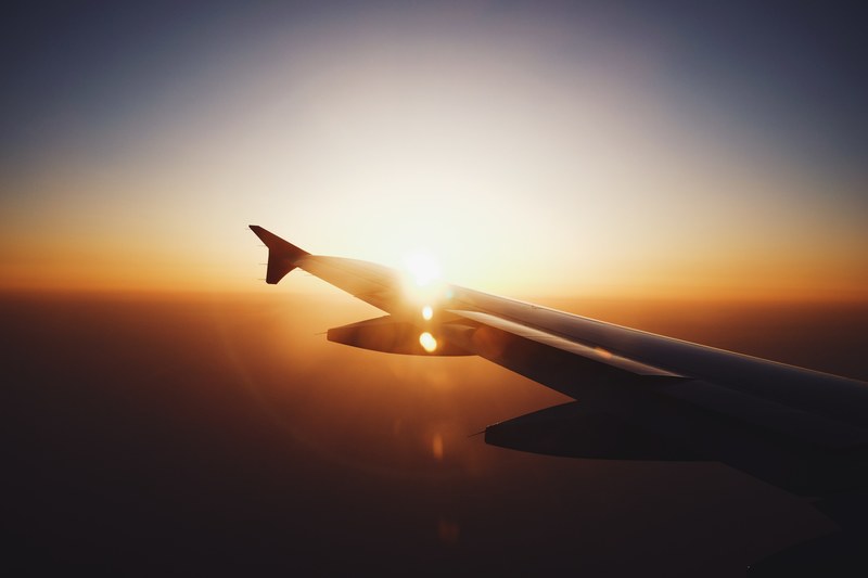silhouette of an airplane wing in flight against the sun setting with lens flare and vignette effects, sunset on plane 4k