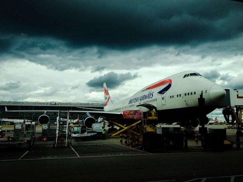 british airways airplane on the ground of an airport under dark cloudy skies, airplane under dark cloudy skies 4k